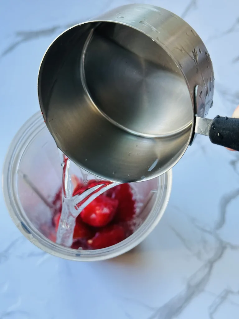 pouring water into a blender to make vitamin c smoothie