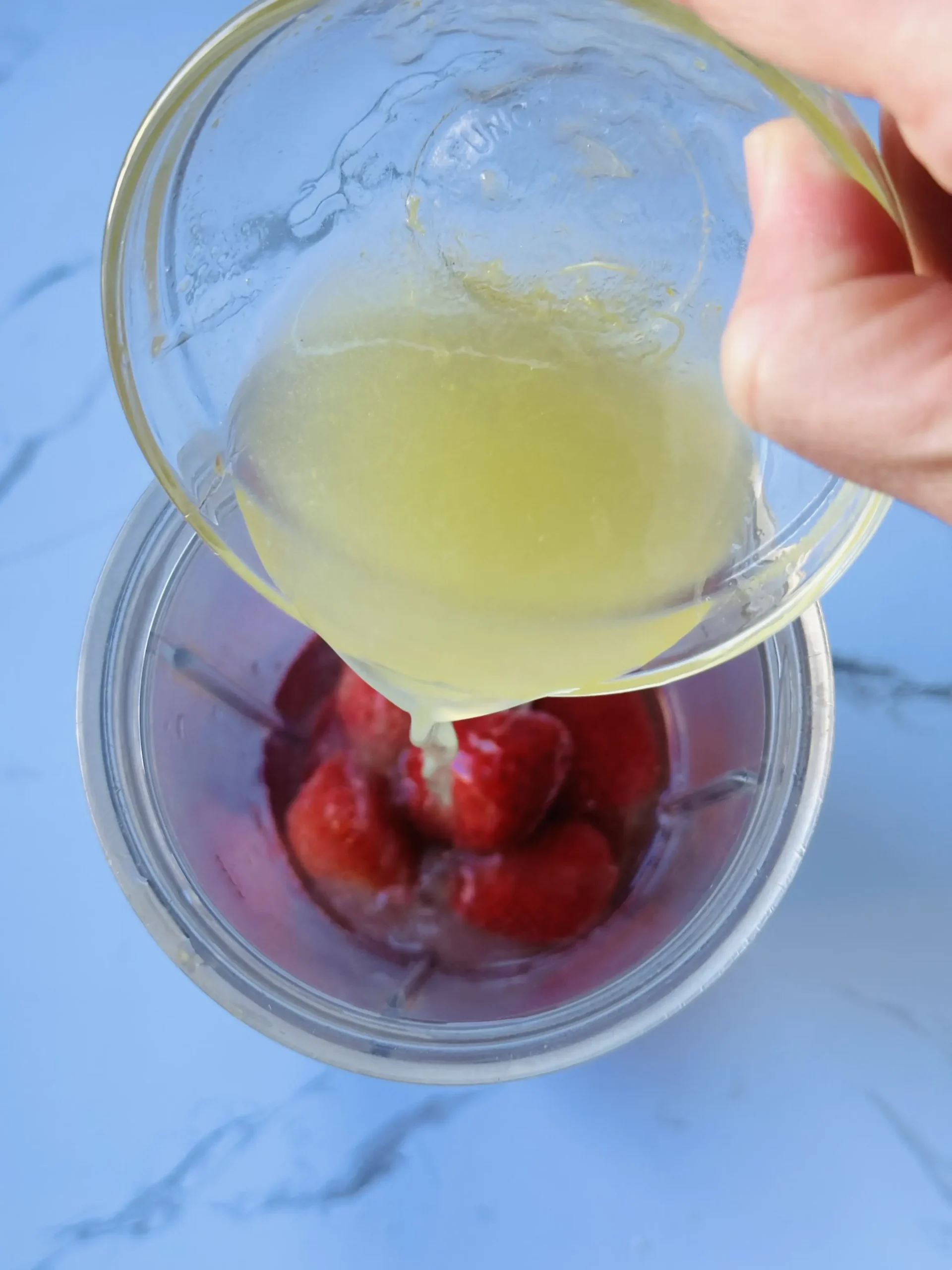 pouring the lime juice and honey into a blender to make vitamin c smoothie