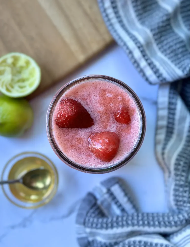 strawberry lime vitamin c smoothie with strawberries in the smoothie and lime and honey on the side