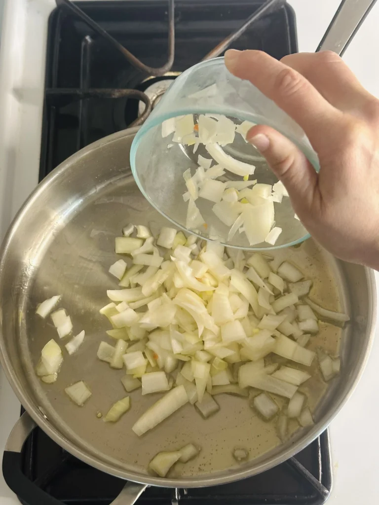 pouring onion into a pan to saute 