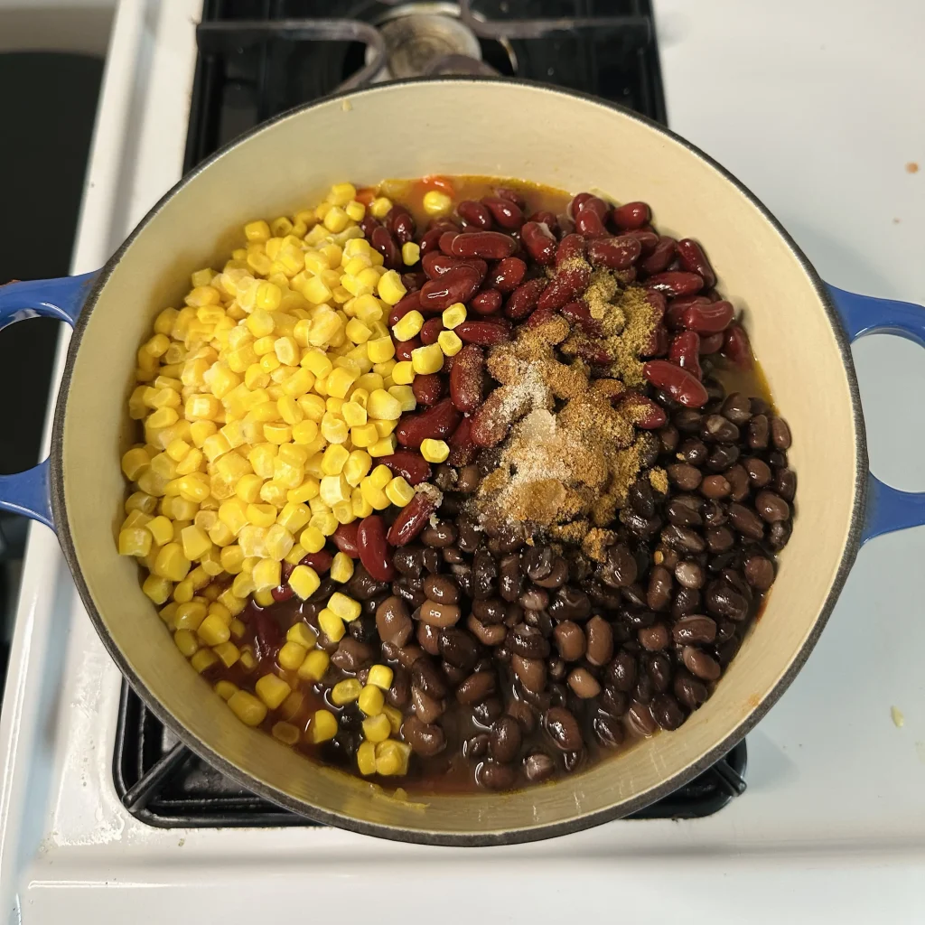 everything added to the cast iron pot in a big unmixed pile for black bean chili with corn