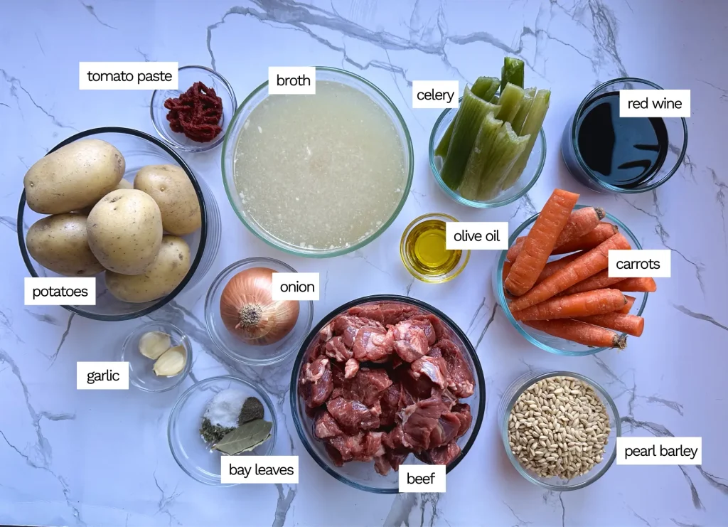 ingredients for beef and barley vegetable soup: beef, broth, potatoes, red wine, carrots, celery, pearl barley and garlic