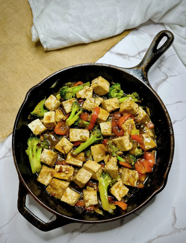 tofu and broccoli stir fry in a cast iron pot on a white marble counter