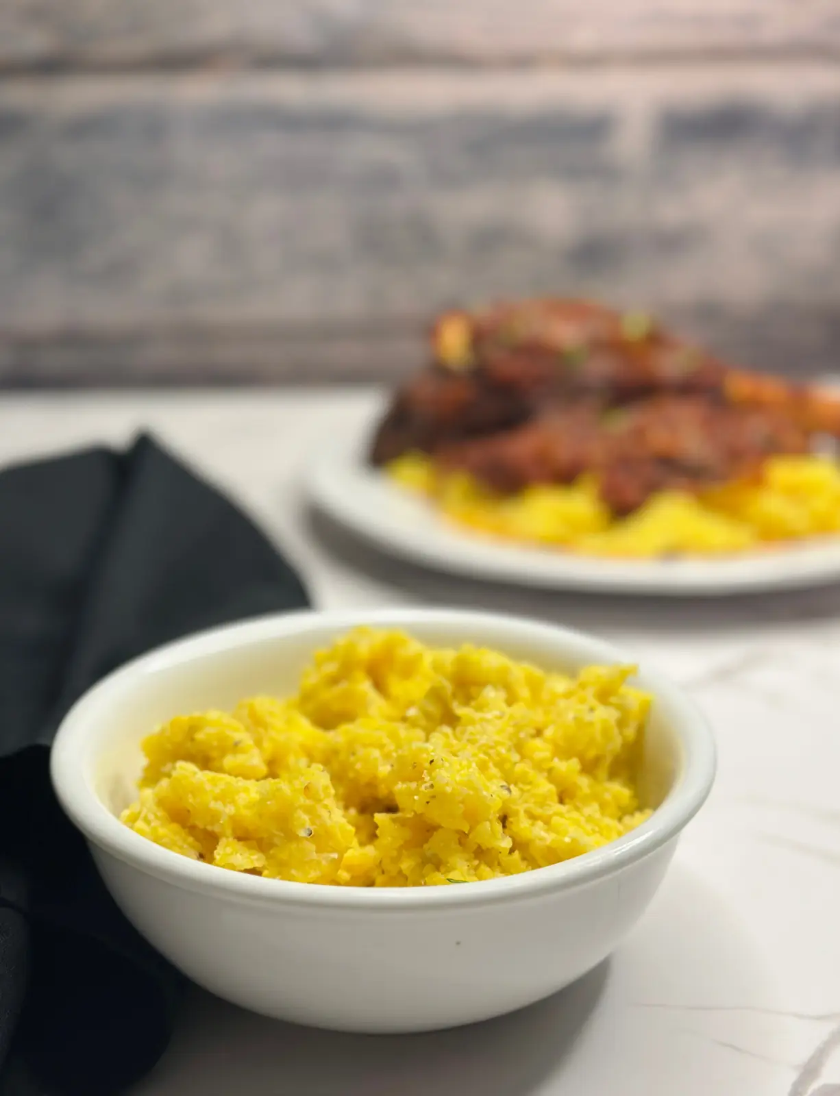 south african pap in a white bowl with lamb in the background blurred