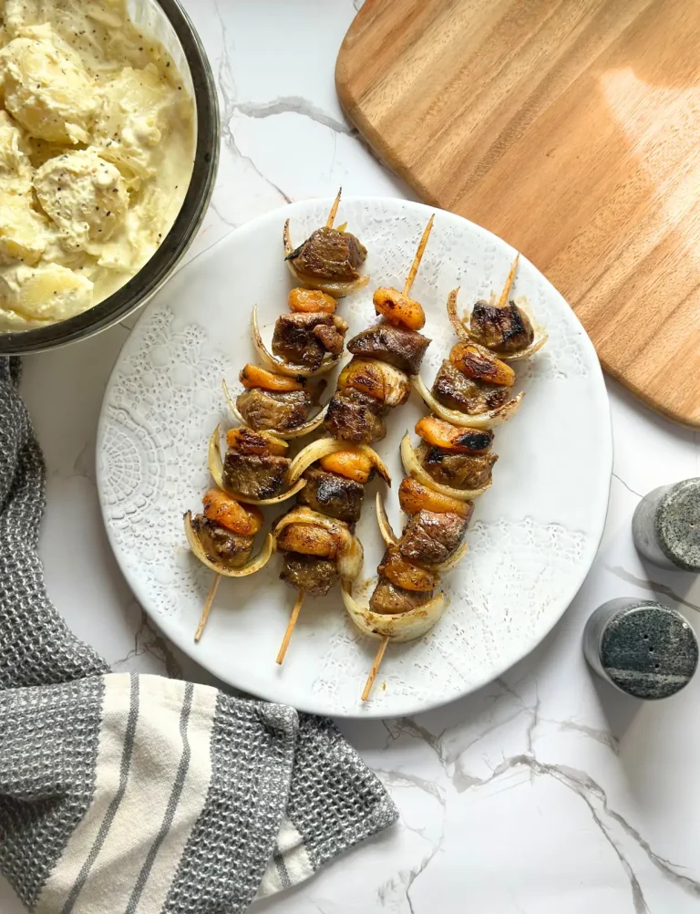 feature image of south african sosaties with lamb, apricot and onion on kebab sticks, charred and served on a white plate