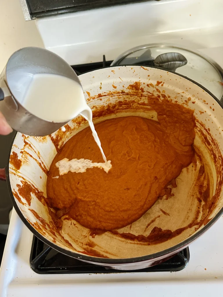 adding cream to the blended sauce back in the pot