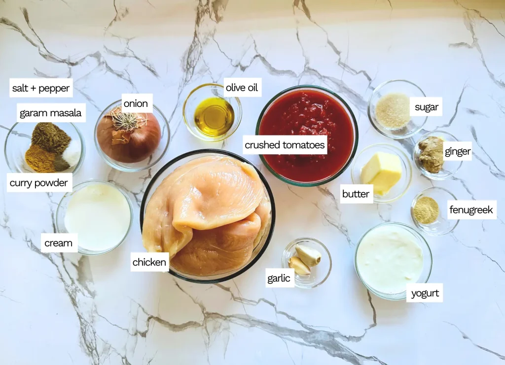 authentic butter chicken ingredients in glass bowls like chicken, yogurt, cream and spices
