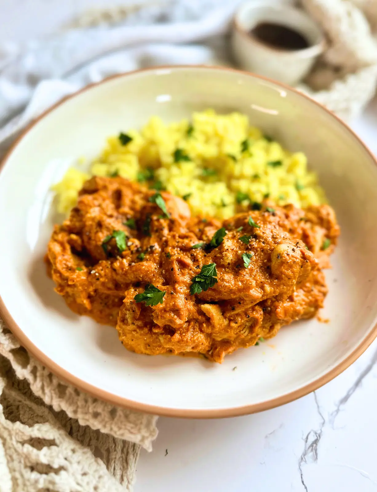 feature image for authentic butter chicken : orange chicken curry on a white plate with yellow rice