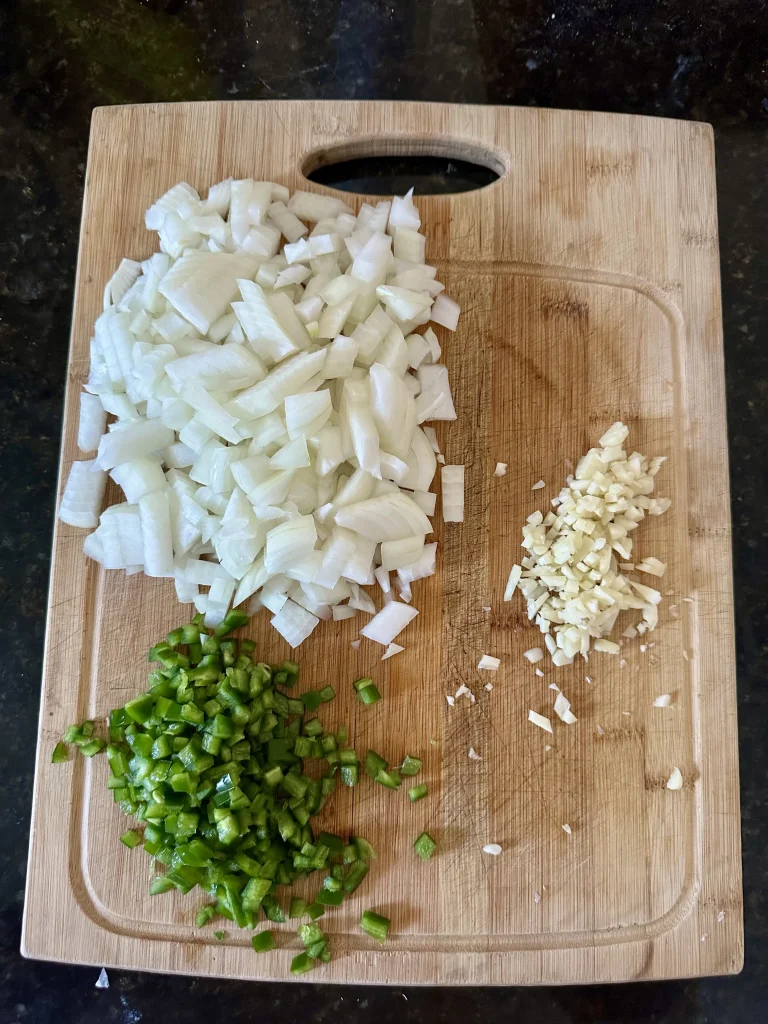 ingredients on a cutting board for pap and sauce including onion, jalapeno and garlic chopped